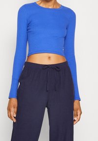 Blå ribbad långärmad crop top som matchas med midnattblå byxor med dragsko. Toppen har en rund halsringning och en figurnära design.