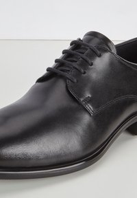 Scarpe eleganti in pelle nera con tomaia liscia, punta rotonda e sei occhielli per i lacci. Si contraddistinguono per i minimi dettagli di cucitura e per il design elegante.