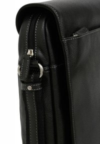 Borsa nera in pelle con superficie testurizzata, chiusura con zip, accessori in argento e cuciture bianche a contrasto lungo i bordi. Presenta una tasca laterale.