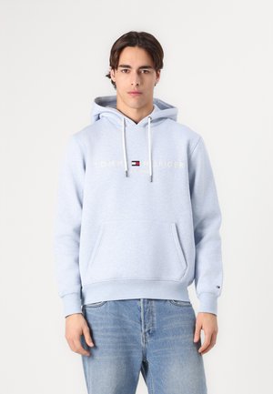 Lichtblauwe hoodie met een kangoeroezak, witte trekkoorden en het "TOMMY HILFIGER"-logo in goud boven de borst. Zachte stoftextuur.