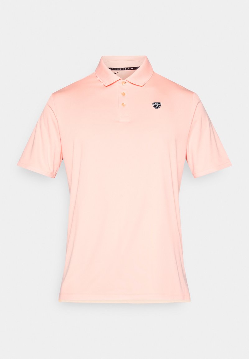 Polo rose clair en matériau lisse, avec un col à trois boutons et un petit logo bleu marine sur la poitrine gauche. Manches courtes.