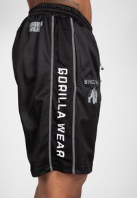 Zwarte mesh sportshorts met een koord in de taille, zilveren accentstiksels en bedrukte logo's aan de zijkanten en achterkant.