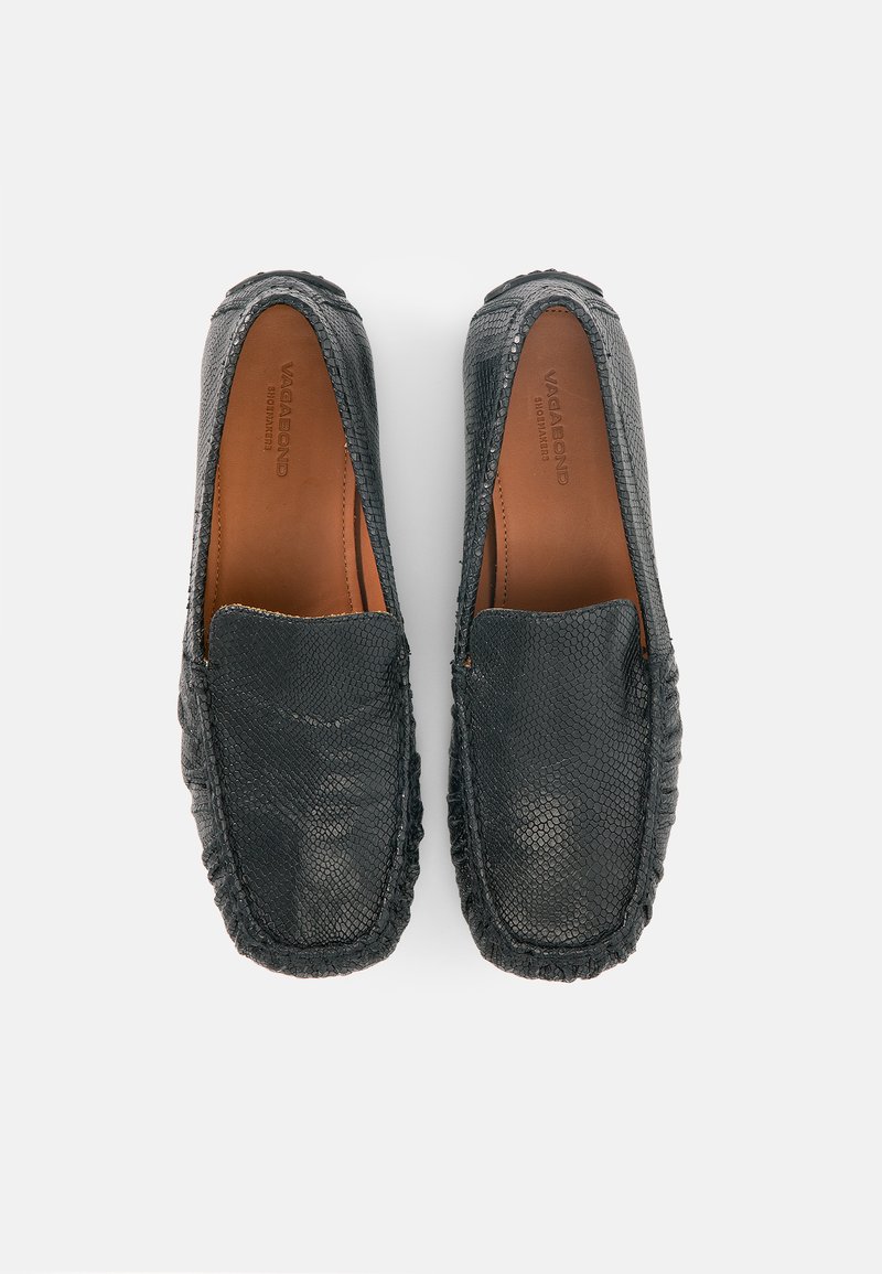 Paar schwarze Slipper aus strukturiertem Leder mit braunen Innensohlen, gebrandmarkt mit "Vagabond", aus der Vogelperspektive auf weißem Hintergrund gezeigt.