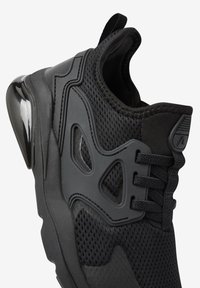 Baskets de sport noires avec un dessus en maille texturée, des accents synthétiques élégants et une semelle brillante. Conçues avec un col rembourré et des lacets.