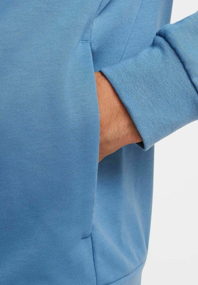 Helles blaues Sweatshirt mit geripptem Bündchen und seitlicher Tasche, aus weichem Stoff mit glatter Textur.