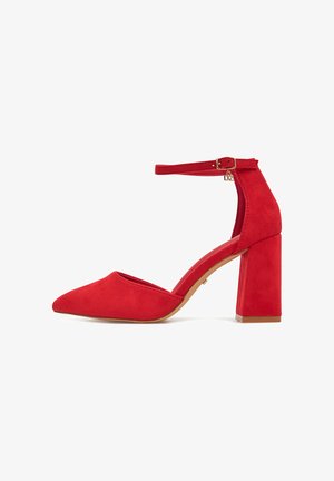 Czerwone zamszowe szpilki z zaostrzonym noskiem i masywnym obcasem. Posiadają pasek wokół kostki oraz dekoracyjny złoty akcent przy pasku.