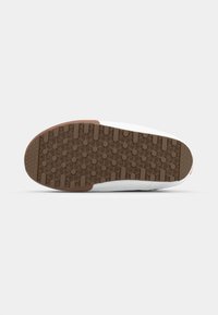 Sål med mønster i lys brunt, designet med en non-slip tekstur med bikake mønster. Kantene er hvite med minimale designdetaljer.