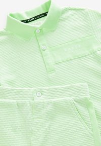 Lys grøn polo-shirt og matchende shorts lavet af tekstureret stof. Har en krave, knapper og en brystlomme med mærkets logo.