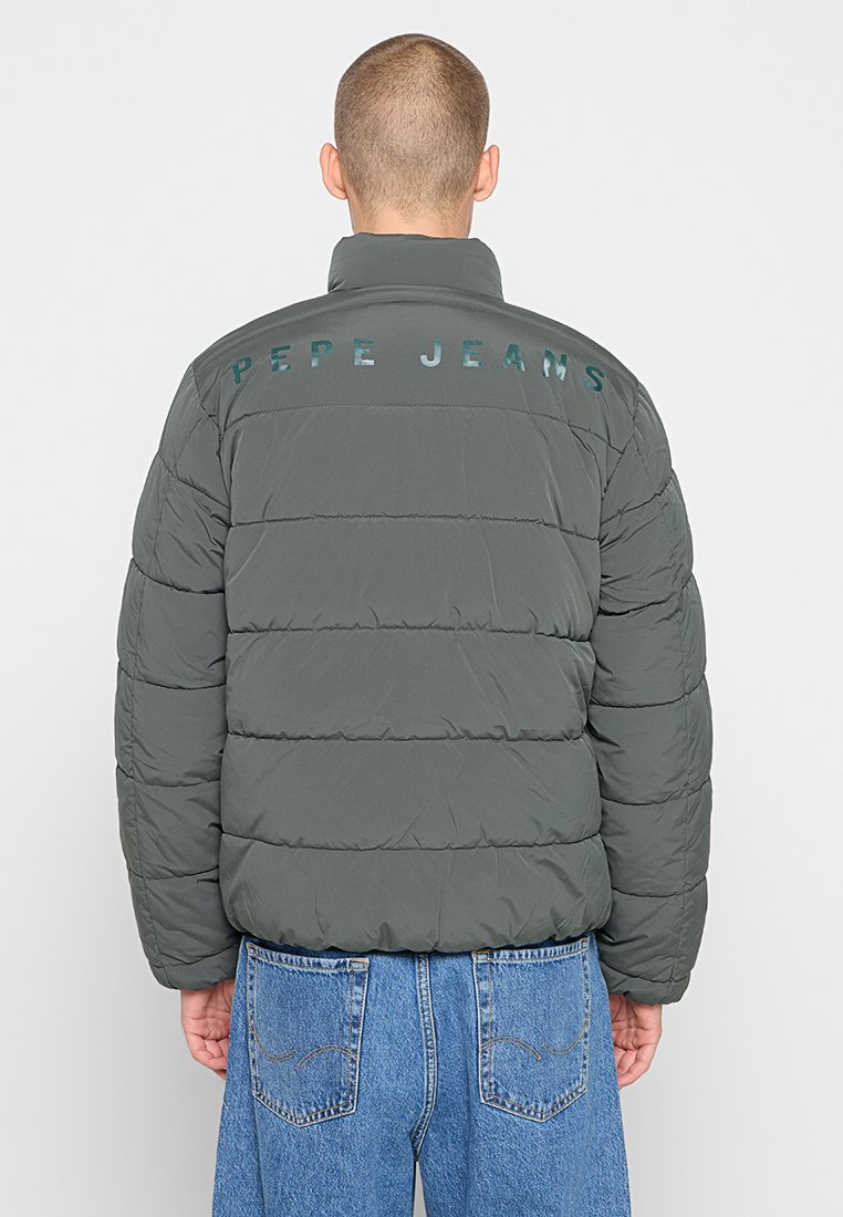 Chaqueta acolchada gris con un cuello alto, featuring un logotipo brillante de "PEPE JEANS" en la parte posterior. La tela parece suave y ligera.