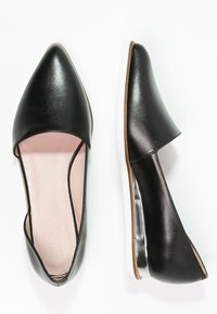 Czarne skórzane płaskie buty z wydłużonym noskiem i wyciętym wzorem. Posiadają białą podeszwę i subtelny metalowy akcent przy pięcie.