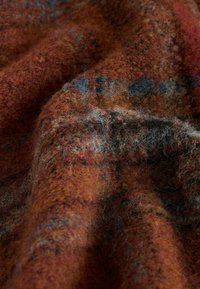 Textured wool fabric featuring warm shades of orange, brown, and flecks of blue and gray, with a soft, fuzzy surface and rich depth.