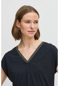 Black V-neck top with short sleeves, featuring a textured gold-threaded trim along the neckline. Soft fabric with a relaxed fit.