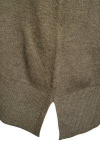 Close-up af brun strikket stof med ribbet kant og en lille central notch i nederkanten.