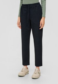 Marineblauwe pantalon met streepjes, voorzien van een elastische tailleband en voorkruiszakken, gecombineerd met lichtgekleurde sneakers. Geverfde stof met een getailleerde pasvorm.