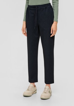 Marineblauwe pantalon met streepjes, voorzien van een elastische tailleband en voorkruiszakken, gecombineerd met lichtgekleurde sneakers. Geverfde stof met een getailleerde pasvorm.