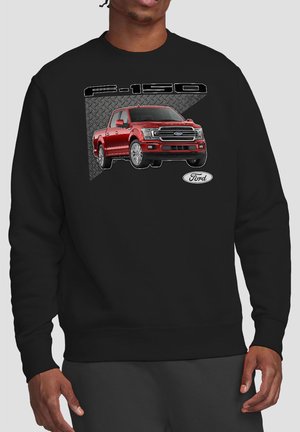 Man wearing black sweatshirt with red Ford F-150 truck graphic and Ford logo on front against a grey textured background.