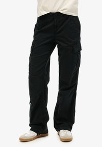 Zwarte cargobroek van duurzame stof, voorzien van meerdere zakken, een relaxed fit en subtiele stiksels langs de naden.