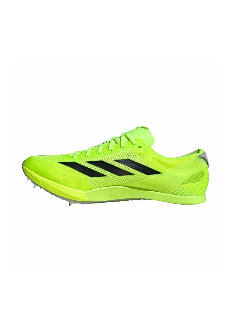 Zapatilla deportiva verde neón con detalles en negro, parte superior de malla texturizada, perfil bajo y placa de clavos para tracción.