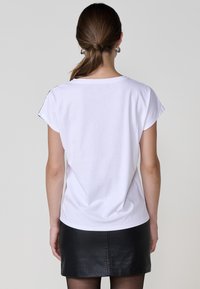 Camiseta de algodón blanca con mangas cortas y un corte relajado. Textura suave, escote redondeado y un back sin adornos.