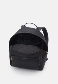 Mochila negra de cuero con superficie texturizada, herrajes dorados, compartimentos con cremallera y un interior de tela negra acolchada.