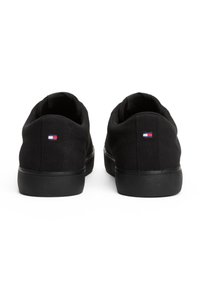 Czarne trampki z płótna o fakturowanej powierzchni, gumowej podeszwie oraz małym logo w kolorach czerwonym, białym i niebieskim na pięcie.