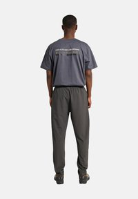 Grijze katoenen t-shirt met tekst op de achterkant, gecombineerd met losse grijze broek. Beide hebben een zachte textuur en een ontspannen silhouet.