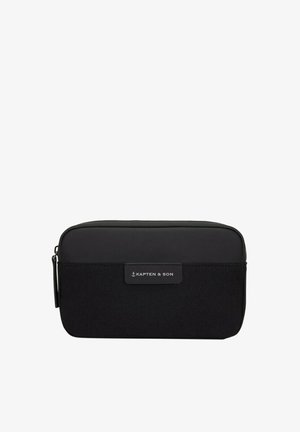 Czarna prostokątna kosmetyczka z materiałową dolną połową, gładką górną połową, zamknięciem na zamek i etykietą "Kapten & Son" na środku z przodu.