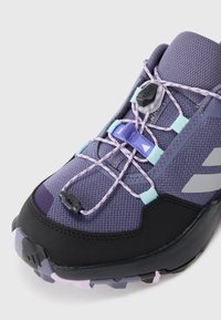 Lila och svart atletisk sko med lavendel elastiska snören, blå snörhållare och en texturerad mesh-överdela för andningsförmåga.