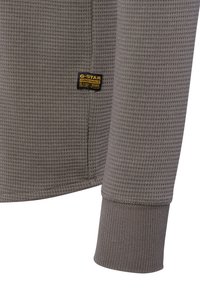 Grau Waffelstrick Langarmshirt mit geripptem Handgelenk und kleinem schwarzen und gelben G-Star Originals RAW Denim Label.