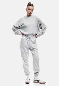 Lys grå oversized sweatshirts med dropped shoulders, parret med tapered grå sweatpants med elastisk talje og manchetter.