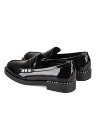 Schwarze Lacklederslipper mit abgerundeter Zehe, dekorativem Steppdetail und silbernen Nietenakzenten entlang der Sohle.