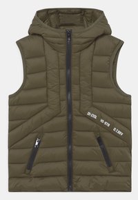 Olivegrön vadderad ärmlös väst med huva, som har en dragkedja framtill, två sidofickor med dragkedja och vita tryckta detaljer på sidan.