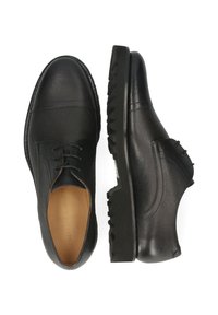 Zwarte leren schoenen met een gestructureerde afwerking, voorzien van een vetersluiting, ronde neus en een rubberen zool met profielen voor extra grip.