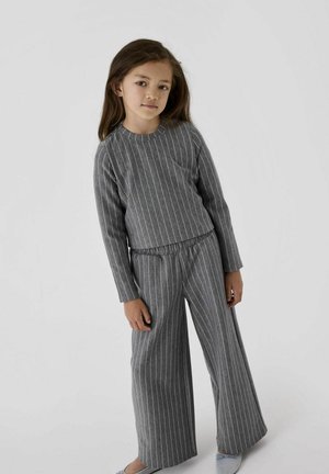 Grårandig loungewear-set med lång ärm, har elastisk midja, vida byxor, mjuk textur och kontrasterande vita ränder.