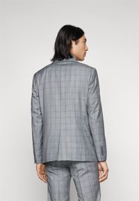 Giacca da abito in plaid grigio con vestibilità su misura, caratterizzata da uno spacco posteriore singolo, rever a punta e dettagli con quattro bottoni sui polsini.