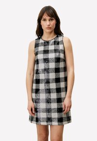 Robe sans manches noire et blanche présentant un motif à carreaux avec des textures variées. Longueur au-dessus du genou avec un col rond.