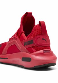 Crvena atletska cipela s mrežastim gornjim dijelom, crnim detaljima, podstavljenim petnim dijelom i istaknutim Puma brandingom. Ima mekan, podstavljen potplat za udobnost.
