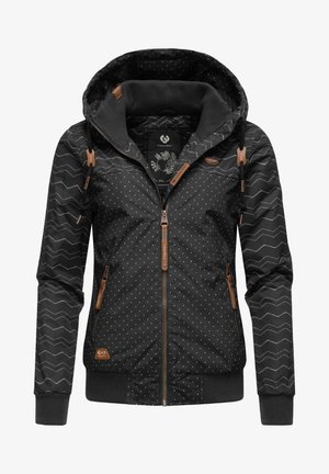 Veste à capuche noire pour femme avec des pois blancs, manches à motif zigzag, fermeture éclair devant et tirettes ainsi que détails en cuir marron.