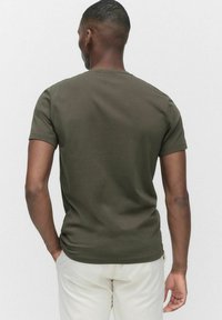 Oliven grøn bomulds T-shirt med rund hals og korte ærmer, der har en glat overflade og en tætsiddende pasform. Ensfarvet bagansigt.