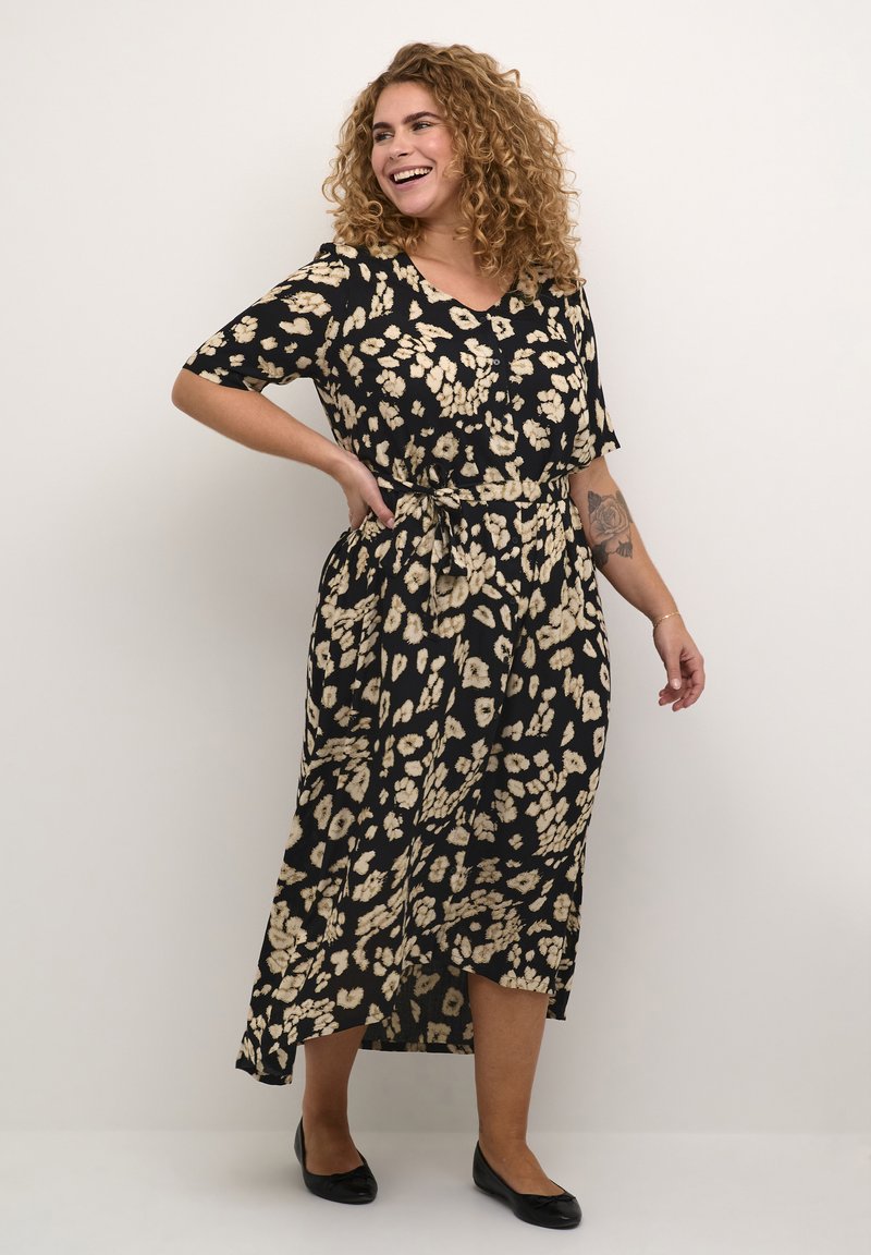 Vestido negro con un patrón floral en tonos crema, mangas cortas, escote en V y un lazo en la cintura, con una silueta fluida hasta los tobillos.