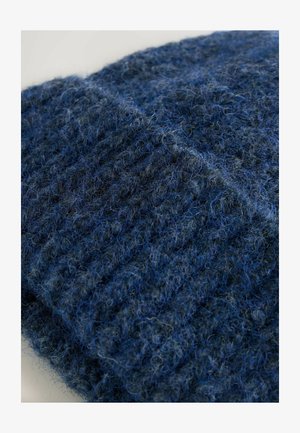 Tejido de lana azul de punto con texturas variadas; presenta una mezcla de fibras azules oscuras y claras, creando una apariencia difusa y un patrón acanalado.