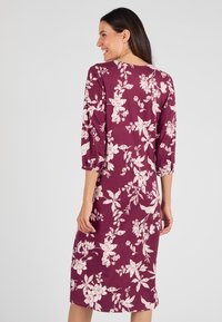Robe bordeaux à manches trois-quarts, ornée d'un motif floral blanc. Tissu doux avec un design à longueur genou et un col rond.