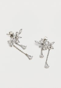 Ezüst virág alakú fülbevalók átlátszó kristály szirmokkal és két, kis láncokkal összekapcsolt, csepp alakú kristály függővel.