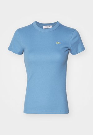 T-shirt azzurro chiaro a righe con maniche corte e design aderente. Presenta un piccolo logo verde Lacoste sul petto.