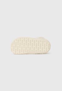 Crocs toffelsula i krämfärg, med mjuk textur, upphöjt mönster med "crocs" logotyp och rundad form.