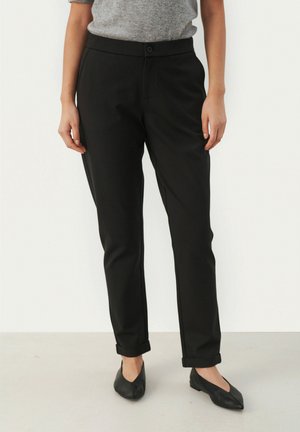 Black tailored trousers with a button closure, smooth fabric, tapered shape, rolled cuffs, and side pockets. Worn with pointed black flats.