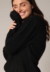 Zwarte geribbelde trui met lange mouwen, gemaakt van gestructureerde brei fabric. Het ontwerp is losjes en comfy, ideaal voor casual wear.