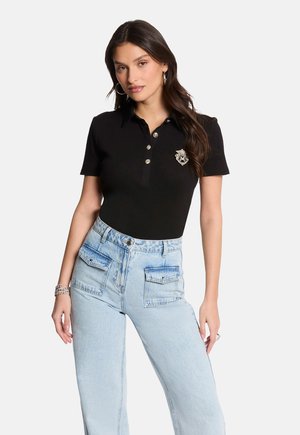 Black polo shirt with a collar and three silver buttons, featuring a decorative emblem. Paired with light blue high-waisted jeans.