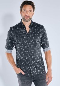 Schwarzes Hemd mit grauem Muster aus Blattformen, kurzen Ärmeln und einem geknöpften Kragen. Der Stoff wirkt glatt und hat einen dezenten Glanz.