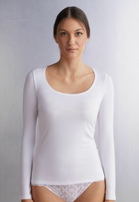 Witte lange mouwen shirt met een brede ronde halslijn, gemaakt van glad materiaal, gecombineerd met witte onderkleding met kant.